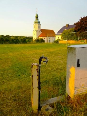Sportplatz und Kirche von Wotrow/Ostro in der Oberlausitz, Kernsiedlungsgebiet der Sorben
